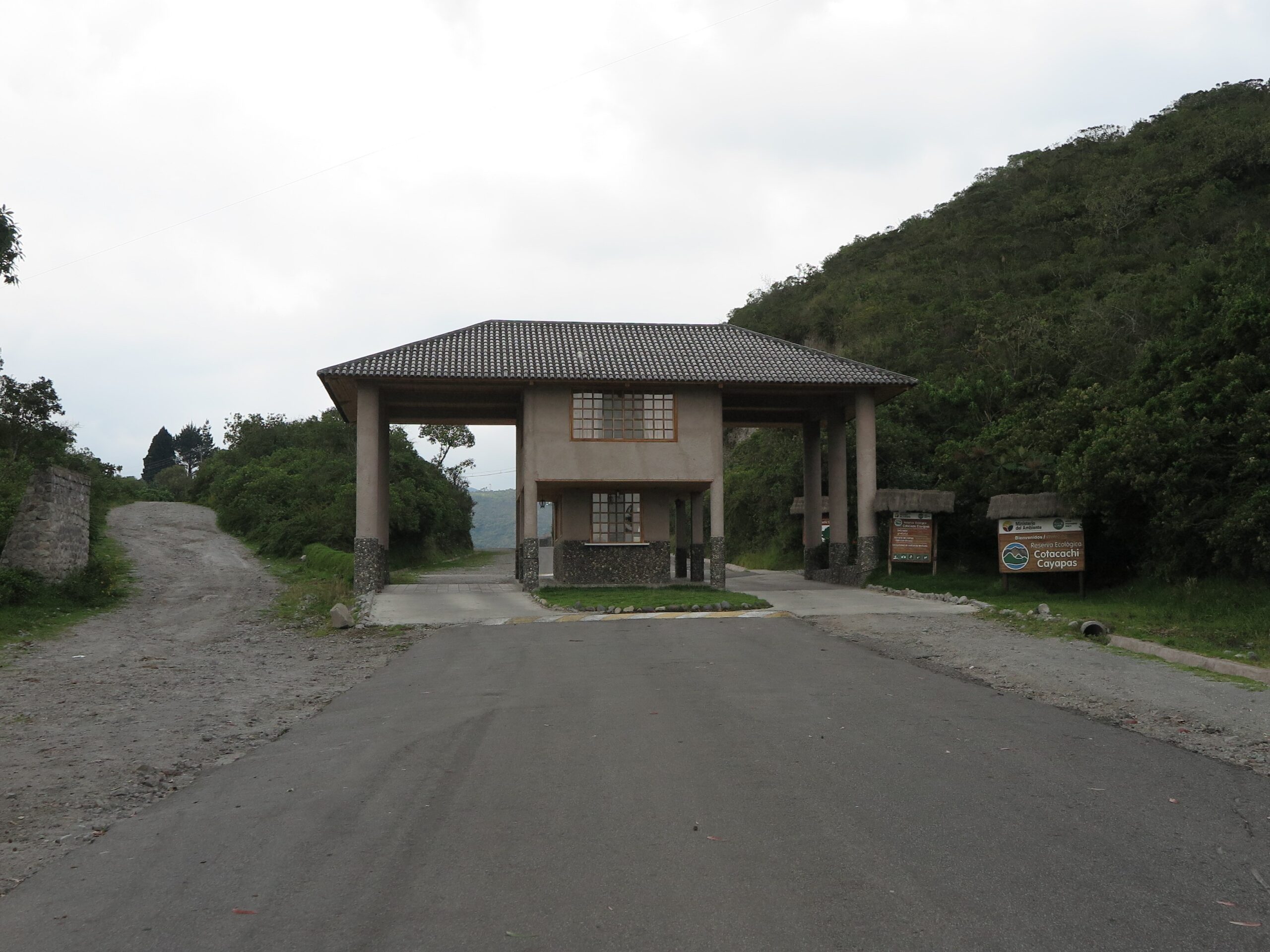 The main entrance gate and visitor center of the Cotacachi Cayapas Ecological Reserve in Ecuador, leading to Laguna de Cuicocha, with lush green mountains in the background.