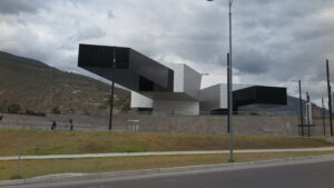 The futuristic UNASUR building with a massive, dramatic cantilever structure at the entrance of Mitad del Mundo (Equator Line) in Quito, Ecuador, under a cloudy sky.