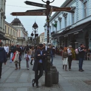 Things to do in Belgrade - A traveler posing next to a directional street signpost on the bustling Kneza Mihaila pedestrian street in Belgrade, Serbia.