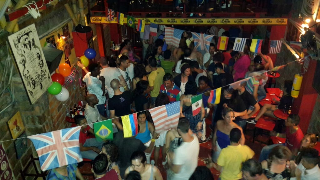 La Topa Tolondra Salsa Bar in Cali Crowds of salsa lovers enjoying a lively night at La Topa Tolondra Salsa Bar in Cali, Colombia, surrounded by international flags and live Latin music.