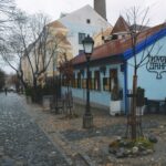 Belgrad'da Gezilecek Yerler - Belgrad Skadarlija'daki tarihi Ima Dana restoranının açık mavi binası ve taş döşeli sokaktaki klasik sokak lambası.