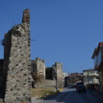 Historic Byzantine walls in Ano Poli, Thessaloniki, beside a paved road and residential buildings.