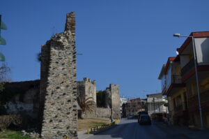 Historic Byzantine walls in Ano Poli, Thessaloniki, beside a paved road and residential buildings.