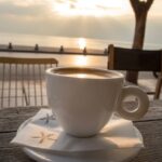 A cup of coffee on a wooden table at a seaside cafe along the Thessaloniki waterfront at sunset.