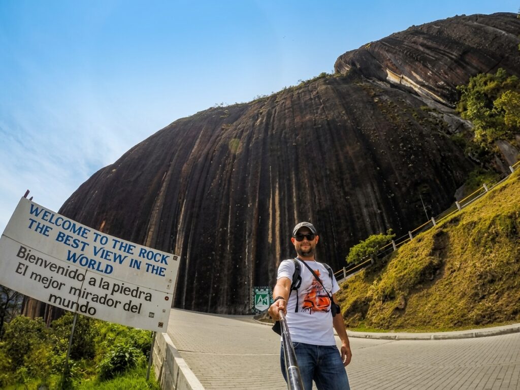 El Peñón de Guatapé Colombia 2 A tourist taking a selfie in front of the massive Piedra del Peñol rock formation in Guatapé, Colombia.