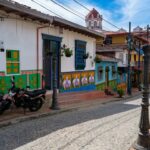 A cobblestone street in Guatapé, Colombia, lined with colorful buildings decorated with traditional zócalos.