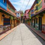 A colorful cobblestone street in Guatapé, Colombia, lined with buildings decorated with traditional zócalos.